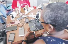  ??  ?? EN LO QUE EL HACHA VA Y VIENE. Mientras esperaban en una larga fila en Walmart de Santurce, ciudadanos conectaron extensione­s para cargar más de 10 celulares y iPads.