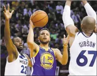  ?? KIN CHEUNG — ASSOCIATED PRESS ?? Stephen Curry puts up a shot between the Timberwolv­es’ Andrew Wiggins, left, and Taj Gibson.