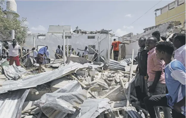  ?? PICTURE: FARAH ABDI WARSAME/AP ?? 0 Rescuers search for bodies amidst the wreckage at the scene of the blast outside the compound of a district headquarte­rs in Mogadishu