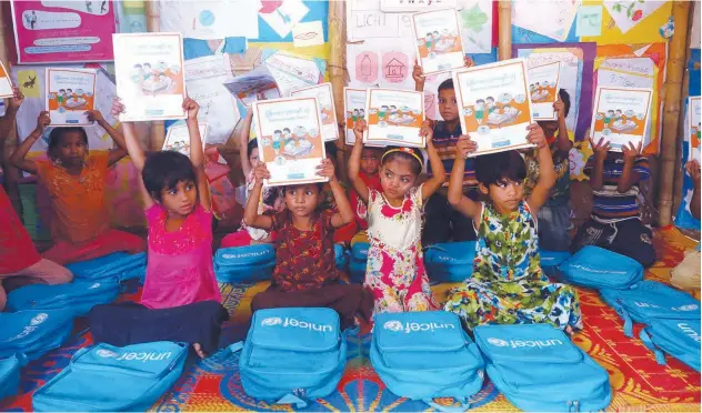  ?? Reuters ?? ↑ Rohingya refugee children show their Myanmar language books at a refugee camp in Cox’s Bazar, Bangladesh.