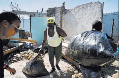  ?? Ramon Espinosa The Associated Press ?? A woman receives donations in El Roble, Cuba, on Wednesday in front of a home destroyed by last week’s tornado.