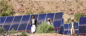  ?? Reuters ?? Farmers walk next to solar panels at a farm in Wadi Dhahr near Sanaa, in Yemen.