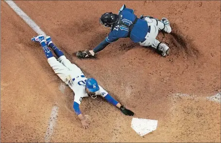  ?? DAVID J. PHILLIP/AP PHOTO ?? Mookie Betts crosses home plate ahead of the tag by Tampa Bay catcher Mike Zunino to score on an infield grounder by Max Muncy during the fifth inning of the Dodgers’ 8-3 win over the Rays in Game 1 of the World Series on Tuesday night in Arlington, Texas.