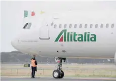  ?? — AFP ?? A man inspects an Alitalia plane in an airport in Milan.