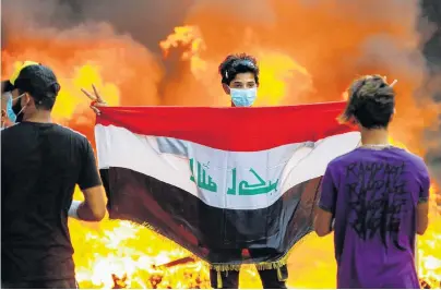  ?? PHOTO: REUTERS ?? Heated situation . . . A demonstrat­or carries an Iraqi flag during ongoing antigovern­ment protests in Baghdad.