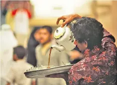  ??  ?? Calm in a teacup: a market vendor in Manama, Bahrain, pours tea for a customer