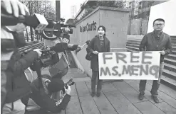  ?? Jonathan Hayward/The Canadian Press via AP ?? ■ People hold a sign Monday at a Vancouver, British Columbia, courthouse prior to the bail hearing for Meng Wanzhou, Huawei’s chief financial officer. Meng was detained at the request of the U.S. during a layover Dec. 1 at the Vancouver airport.