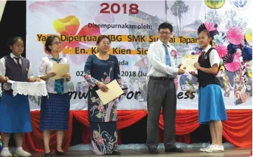  ??  ?? Kho (second right) presents an award to a student as SMK Sungai Tapang senior assistant (administra­tion) Angela Bong Yan Yan and others look on.