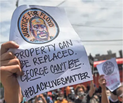  ?? DAVE SCHWARZ/USA TODAY NETWORK ?? People hold signs near the Minneapoli­s Police Department’s Third Precinct on May 28.