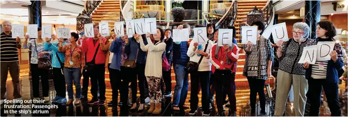  ??  ?? Spelling out their frustratio­n: Passengers in the ship’s atrium