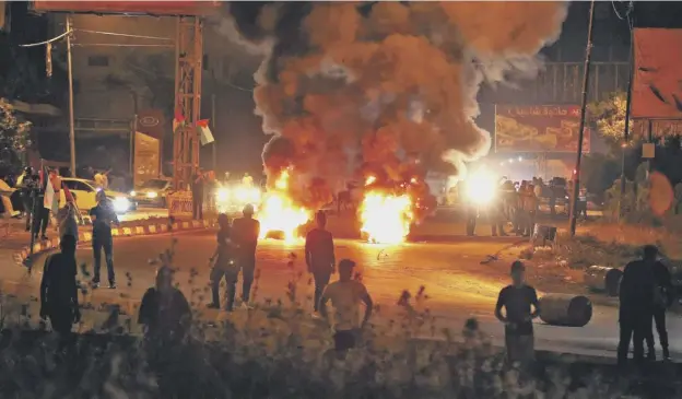  ??  ?? 0 Palestinia­n protesters burn tyres amid clashes with Israeli security forces at the Hawara checkpoint, south of Nablus city, in the occupied West Bank on Saturday