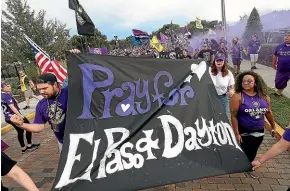  ??  ?? Football fans in Orlando, Florida carry a sign yesterday supporting the victims of the El Paso and Dayton mass shootings. US President Donald Trump’s planned visits to both cities have drawn criticism.