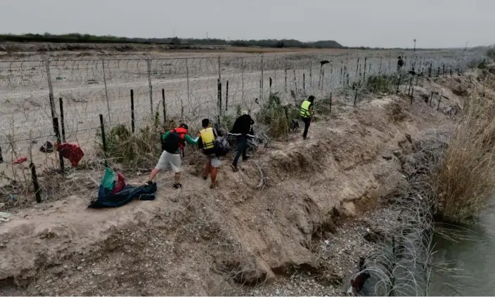  ?? ?? Migrants at border crossing in Eagle Pass, Texas, ahead of the anticipate­d visit by Donald Trump on Thursday. Photograph: Anadolu/Getty Images