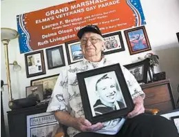  ?? REED SAXON/AP ?? In 2016, Lauren Bruner holds a 1940 photo of himself at his home in La Mirada, Calif. Divers will place his ashes in the wreckage of his ship this weekend in Pearl Harbor.