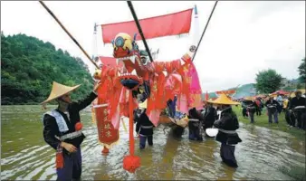  ?? HUANG XIAOHAI / FOR CHINA DAILY ?? Ethnic Miao people adorn a wooden dragon boat with silk to pray for good weather and a bumper harvest at the start of the Miao Dragon Boat Festival in Taijiang county, Guizhou province, on Sunday. The festival was added to the national intangible...