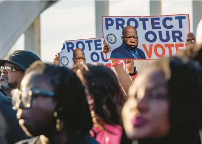  ?? BRANDON BELL/GETTY ?? People with posters featuring late U.S. Rep John Lewis march on March 6 across the Edmund Pettus Bridge in Selma, Ala.