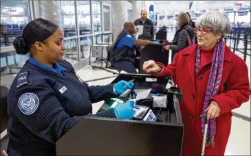  ?? STEVE SCHAEFER / SPECIAL TO THE AJC ?? TSA agent Aftan Zayas helps passengers get through security at Hartsfield-Jackson Internatio­nal Airport in November. TSA workers are considered essential and are working without pay during the partial government shutdown, which is now likely to extend into the new year.