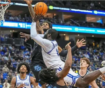  ?? Frank Franklin II/Associated Press ?? Seton Hall’s Dylan Addae-Wusu, center, falls into Marquette’s David Joplin while going up for a shot Saturday in Newark, N.J. Seton Hall defeated No. 7 Marquette, 78-75.