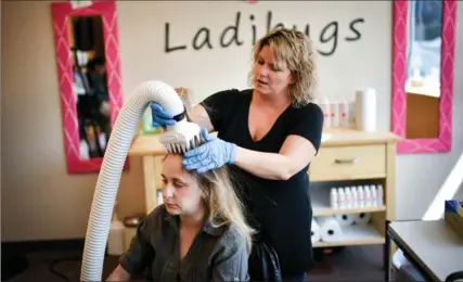  ?? GLEN STUBBE, MINNEAPOLI­S STAR TRIBUNE ?? Ladibugs manager Christina Doran treats a client with an AirAlle device, which uses air hot enough to kill lice but not burn the client.