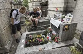 ?? MICHEL EULER AP ?? Joachim Tittmar from Germany, left, Walter Homburg of The Netherland­s, center, and his girlfriend Kate Schirm gather at the tomb of rock singer Jim Morrison at the Pere-Lachaise cemetery in Paris on Saturday, the 50th anniversar­y of the rock icon’s death.