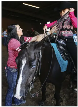  ?? Arkansas Democrat-Gazette/THOMAS METTHE ?? Megan Tutor of Greers Ferry helps her 9-year-old sister, Lacy Tutor, get ready to compete during Saturday’s horse show.