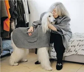  ?? — THE ASSOCIATED PRESS ?? Designer Giovanna Temellini kisses her dog Ulisse, an Afghan greyhound, wearing a winter coat at the Temellini manufactur­e headquarte­rs, in Milan. Temellini launched Dog a Porter a year ago alongside her 20-year-old eponymous clothing line for women.