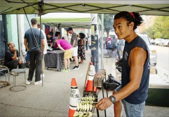  ?? Ben Braun/Post-Gazette ?? Rocky Cristobal of Kraynick’s Bike Shop tends to grilling duties on Friday in Garfield. Between 4800 and 5500 Penn Avenue, artists and business owners host an art crawl called “Unblurred” on the first Friday of each month. The next event is scheduled for Sept. 3.