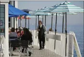  ?? ERIC RISBERG — THE ASSOCIATED PRESS FILE ?? A waiter walks past tables of people dining outdoors at Scoma’s restaurant in Sausalito.