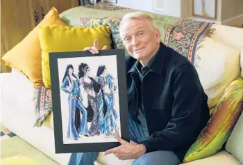 ?? CHRIS PIZZELLO/AP ?? Costume and fashion designer Bob Mackie poses with a sketch of clothing designs he did for Cher throughout her career, at his home in Palm Springs, California. The sketch was used for the 2019 Broadway show “The Cher Show.”