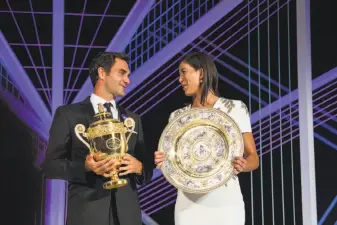  ?? Thomas Lovelock / All England Lawn Tennis Club ?? Wimbledon singles champions Roger Federer of Switzerlan­d and Garbiñe Muguruza of Spain compare hardware at the Champions Dinner in London.