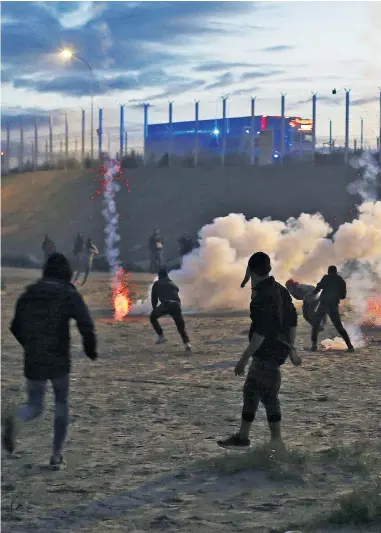  ??  ?? The fate of young migrants is sealed by French and British officials. Right, French riot police officers fire tear gas canisters during clashes with migrants yesterday