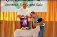  ??  ?? The Champion Market Lamb was shown by Brooke Mazepink of Parkesburg and was purchased by Richard and Diane Hicks of Unionville for a record breaking $10.50/ lb. Pictured with Brooke is Mr. Hicks.