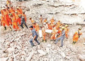  ?? — Reuters photo ?? Rescue workers carry the body of a victim at the site of a collapsed residentia­l building at Shah Beri village in Greater Noida, India.