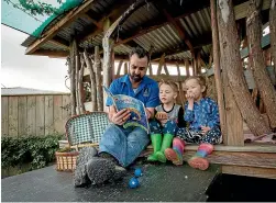  ?? WARWICK SMITH/STUFF ?? Robert Jensen, head teacher at Tu¯¯ı Young Investigat­ors, reads to siblings Samuel and Sienna Porteous.