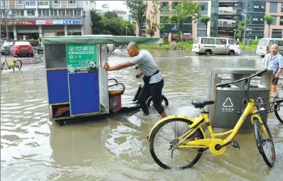  ?? ZHANG LANG / CHINA NEWS SERVICE ANHUI ?? A man pushes his vehicle in a flooded street in Chengdu, Sichuan province, on Thursday.