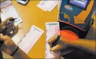  ?? Elizabeth Brumley ?? People fill out numbers on Powerball tickets at the Primm Valley Lotto Store last week.
Las Vegas Review-journal