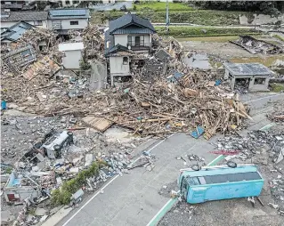  ?? CARL COURT GETTY IMAGES ?? Overturned vehicles lie next to a ruined house that is surrounded by debris and driftwood after the nearby Kuma River flooded during torrential rain, on Wednesday in Kuma, Japan.