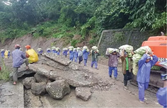  ?? Photo by Mayor Manny Fermin/Kapangan ?? TO THE MARKET. Porters carry assorted vegetables after a portion of the Gov. Bado Dangwa National Road along Gambang Cuba, Kapangan was closed due to landslide brought about by the Southwest Monsoon (Habagat) and typhoon Hanna that saturated the terrain to cause slippage.