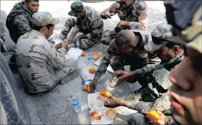  ??  ?? Iraqi soldiers eat their meal along the road beside their armoured fighting vehicles in western Mosul. PICTURE: REUTERS