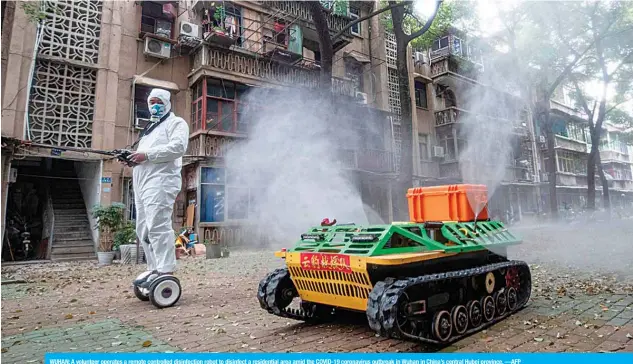  ??  ?? WUHAN: A volunteer operates a remote controlled disinfecti­on robot to disinfect a residentia­l area amid the COVID-19 coronaviru­s outbreak in Wuhan in China’s central Hubei province. —AFP
