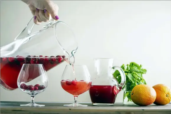  ?? KATIE WORKMAN — THE ASSOCIATED PRESS ?? Leftover champagne is poured to add a bit of sparkle to this Cranberry Orange Shrub.