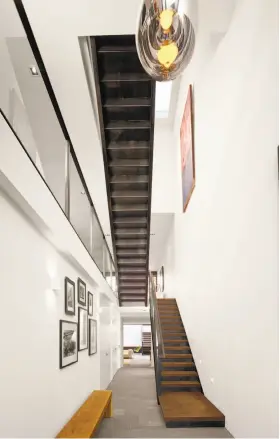  ?? Cesar Rubio ?? Left: Designed by Dumican Mosey Architects, this Noe Valley home opens to a towering foyer with a turned hardwood staircase. Below left: A staircase with floating tread stands beneath a light well in this Noe Valley home. Below right: The back of this...