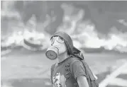  ?? Ariana Cubillos ?? A protester stands in front of a burning barricade Monday on a highway in Caracas, Venezuela. Thousands shut down the city’s main highway.