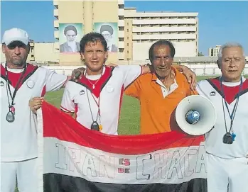  ??  ?? Arraigo. El técnico con sus colaborado­res y una bandera de Chacarita, donde es ídolo.