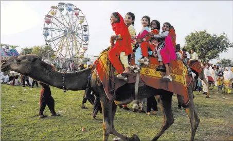  ?? K.M. Chaudary ?? The Associated Press Children ride a camel Sunday during an outing with their families at a fair on the bank of the Ravi River at Lahore, Pakistan, to celebrate the Muslim Eid al-fitr holiday. Eid al-fitr marks the end of the Islamic holy month of...