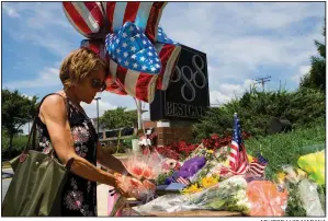  ?? AP/JOSE LUIS MAGANA ?? Neighbor Elly Tierney places flowers Friday at a makeshift memorial outside the office building housing the Capital Gazette newspaper in Annapolis, Md.