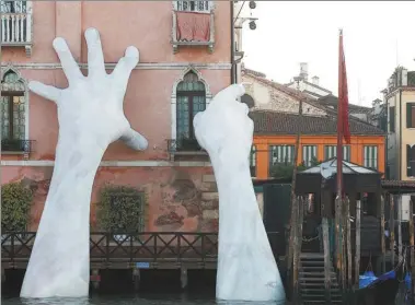  ?? STEFANO RELLANDINI / REUTERS ?? Italian artist Lorenzo Quinn’s installati­on called on Saturday. is seen on Ca’ Sagredo palace during the 57th La Biennale of Venice in Italy