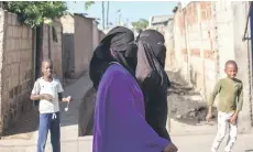  ?? ?? Two Muslim women walk through one of the streets of the Mafalala neighbourh­ood in Maputo.