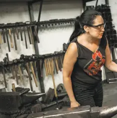  ??  ?? Above: Blacksmith­ing instructor Celeste Flores works in the shop. The Cruucible offers more than 20 areas of study with department­s such as glass blowing, woodworkin­g, welding and many more. Left: Idalis Price, left, and Emilie Abel walk through...