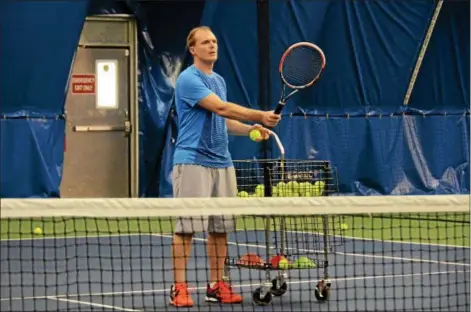  ?? KELSEY LEYVA — THE MORNING JOURNAL ?? Brian Dehaven, program director at the Avon Oaks Tennis Center, hits balls to his son, 12-year-old Logan Dehaven, April 12 during a practice session at the tennis center’s indoor facility, 32300 Detroit Road, in Avon.